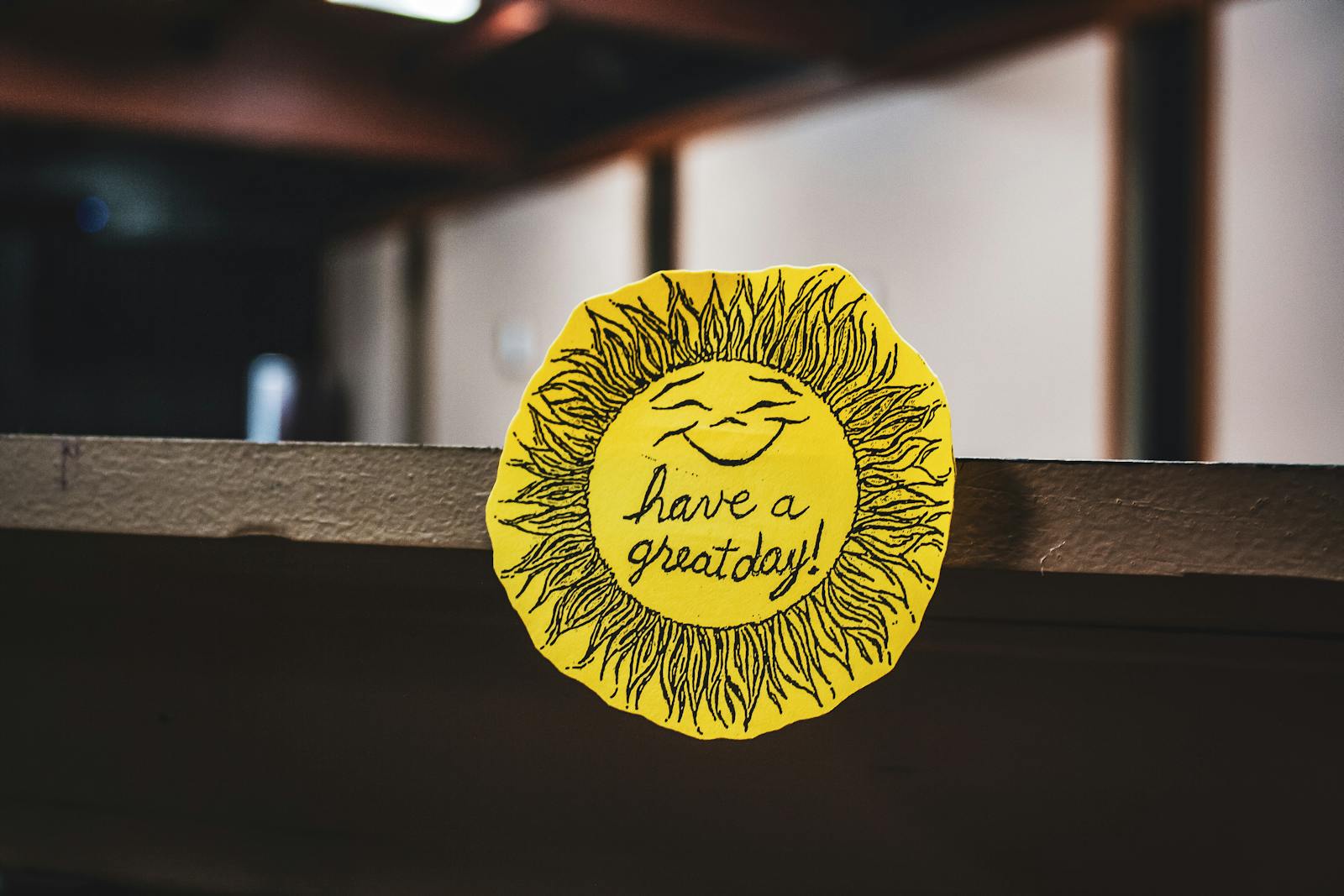 Yellow paper sun with a smile and 'Have a great day!' message on a shelf.